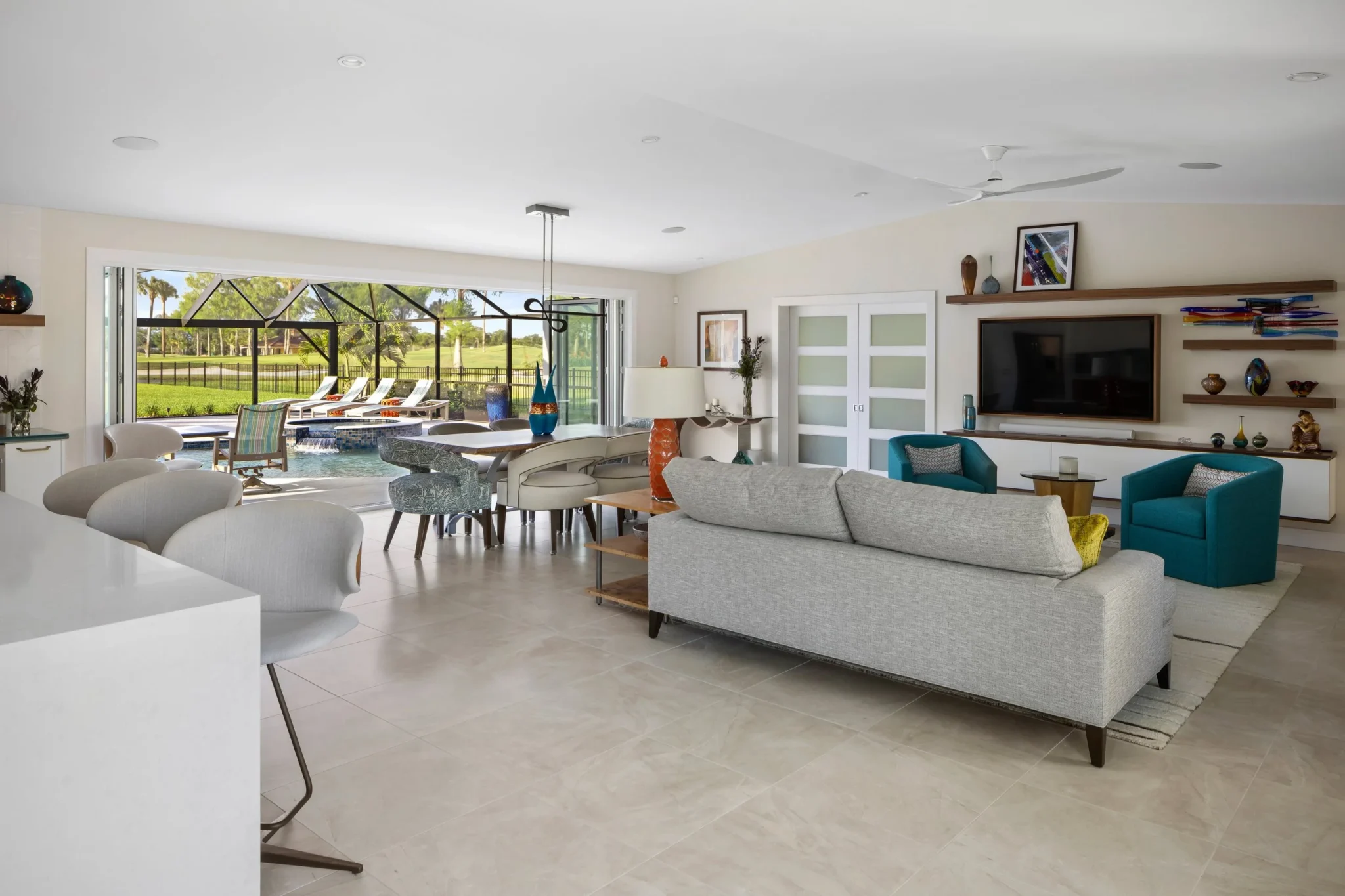Living room with beige tiled floors, white walls, modern furniture including a sofa and armchairs