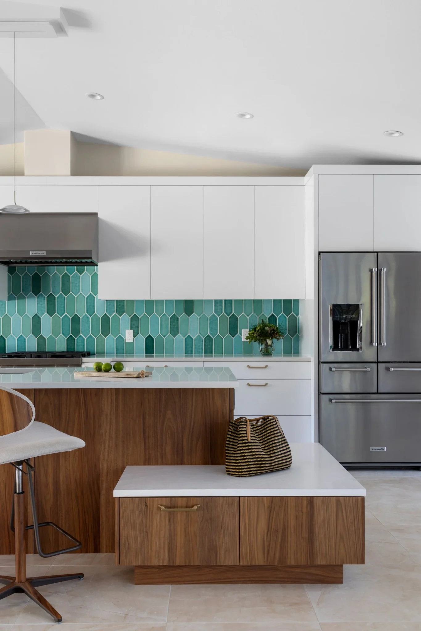 Modern kitchen with white upper cabinets, a teal geometric backsplash, wooden lower cabinets, a stainless steel refrigerator