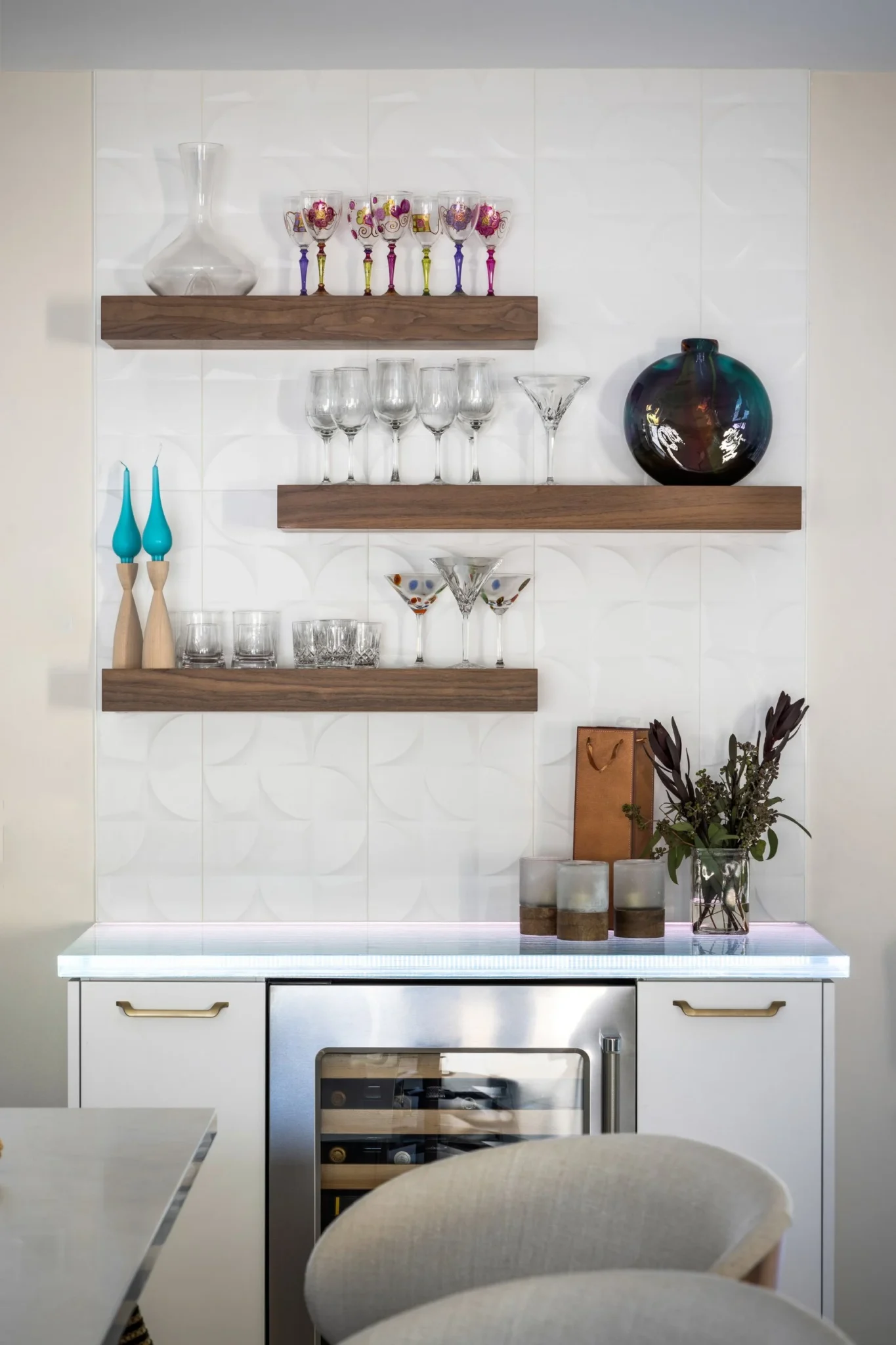 Decorative kitchen shelf display with glassware, vases, candles, and a flower arrangement