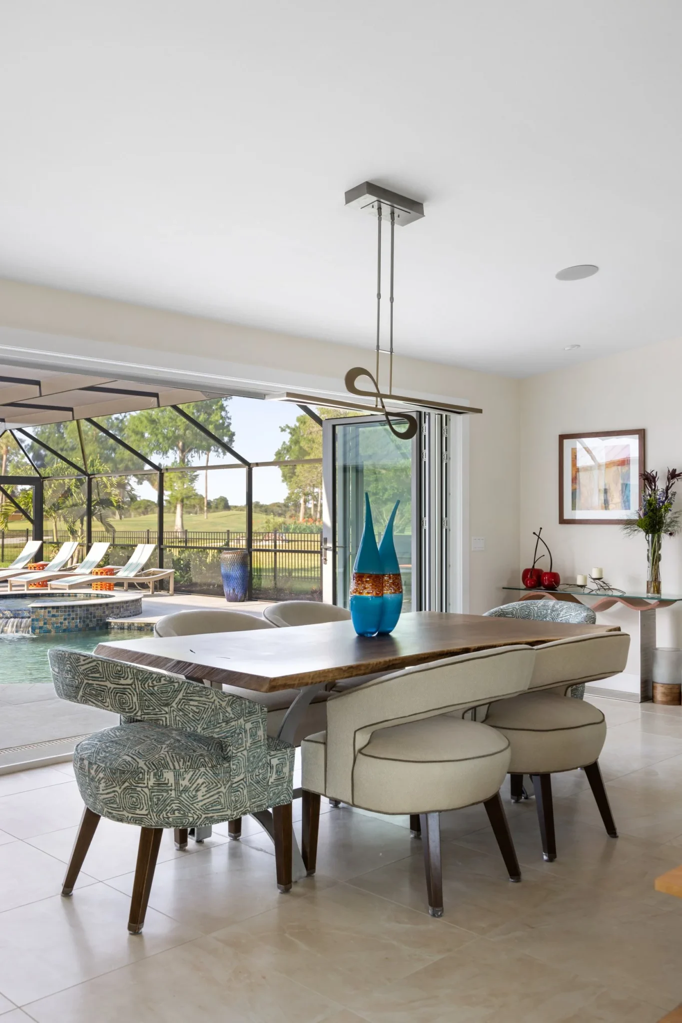 Dining area with a wooden table, upholstered chairs, and decorative glass vases
