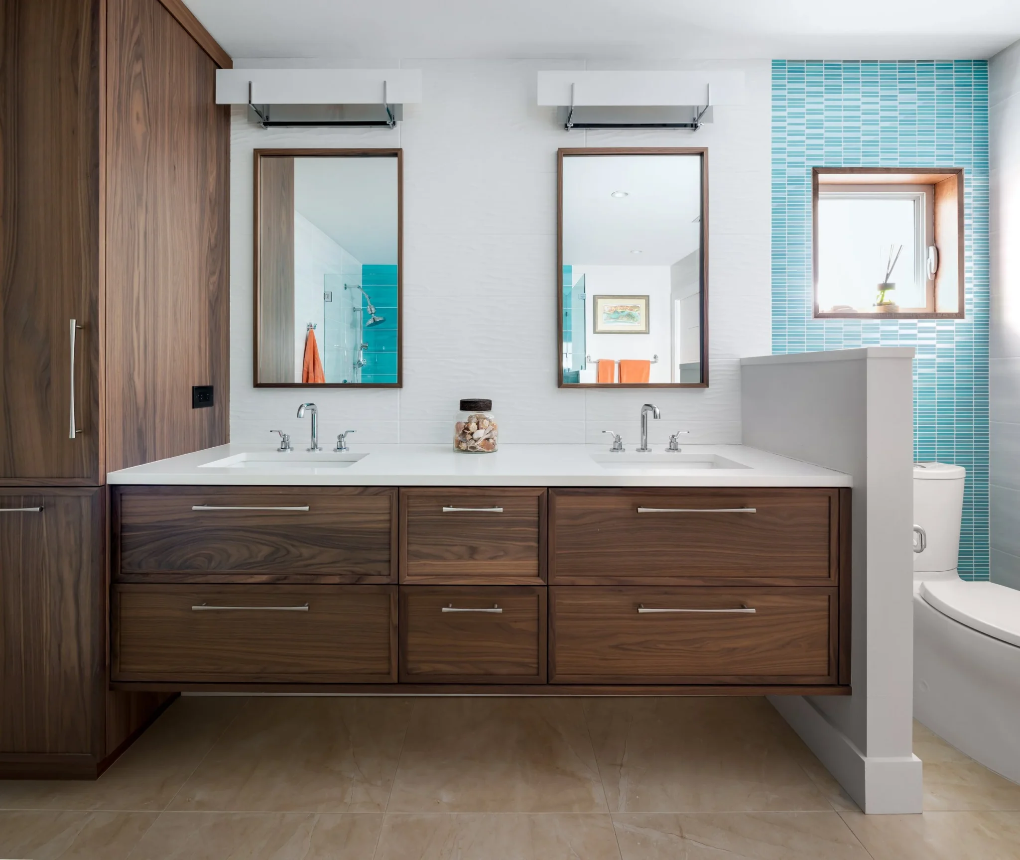 Modern bathroom with a double vanity featuring wooden cabinets, two rectangular mirrors, and a jar of seashells on the countertop