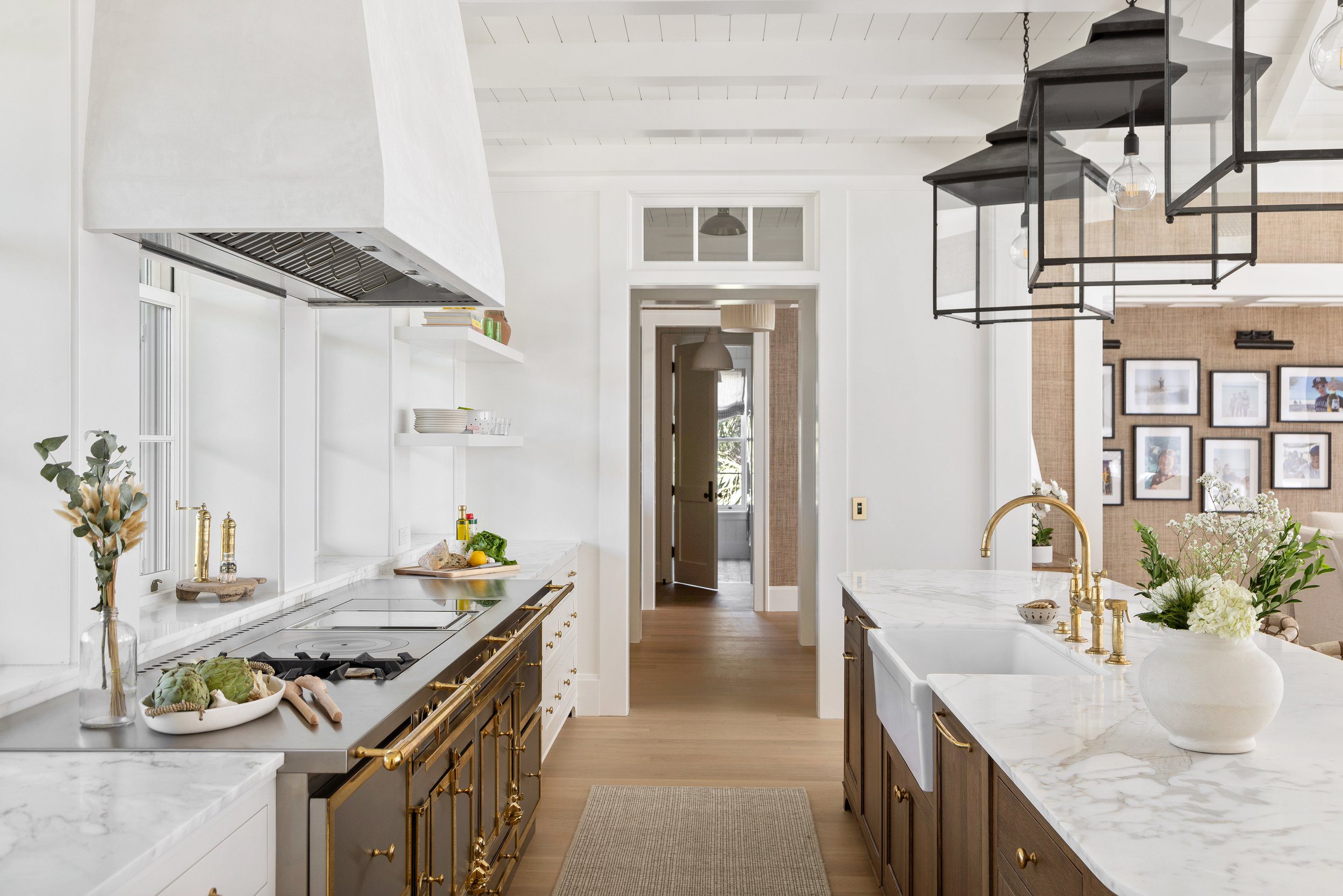 Kitchen with marble counters, lantern pendants and a plaster range hood at the North Shore Residence