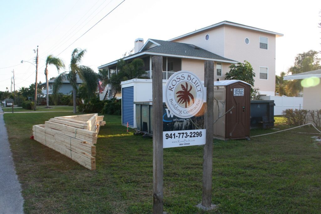 Ross Built Building Contractor job site sign with a color palm logo on two wooden posts, 2011