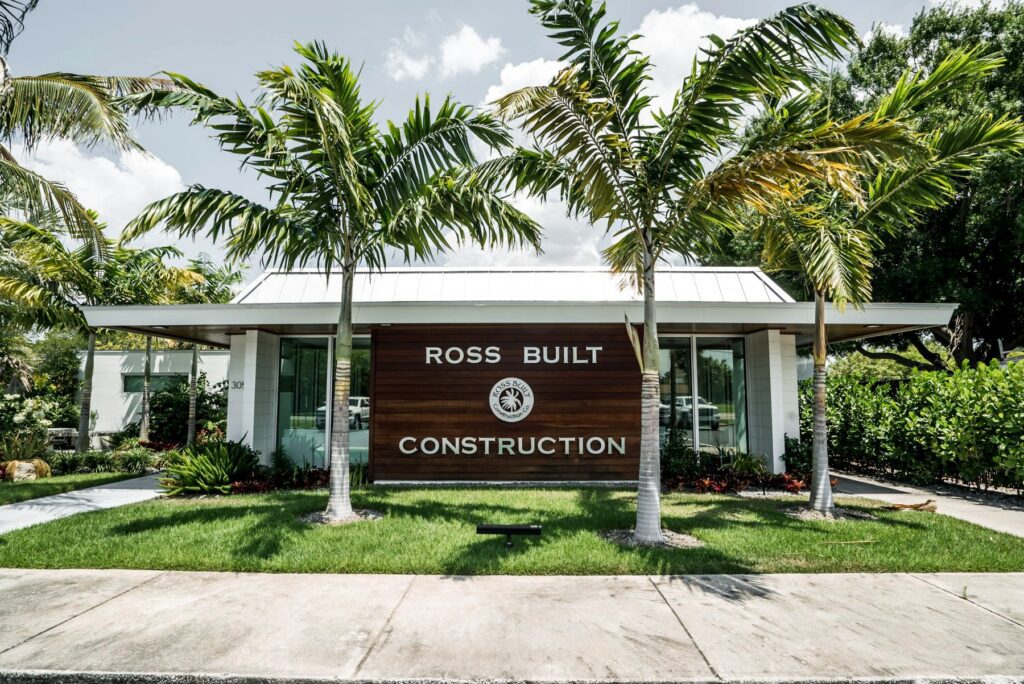 The Ross Built office on 67th Street after the renovation, with a wood sign wall and palms out front