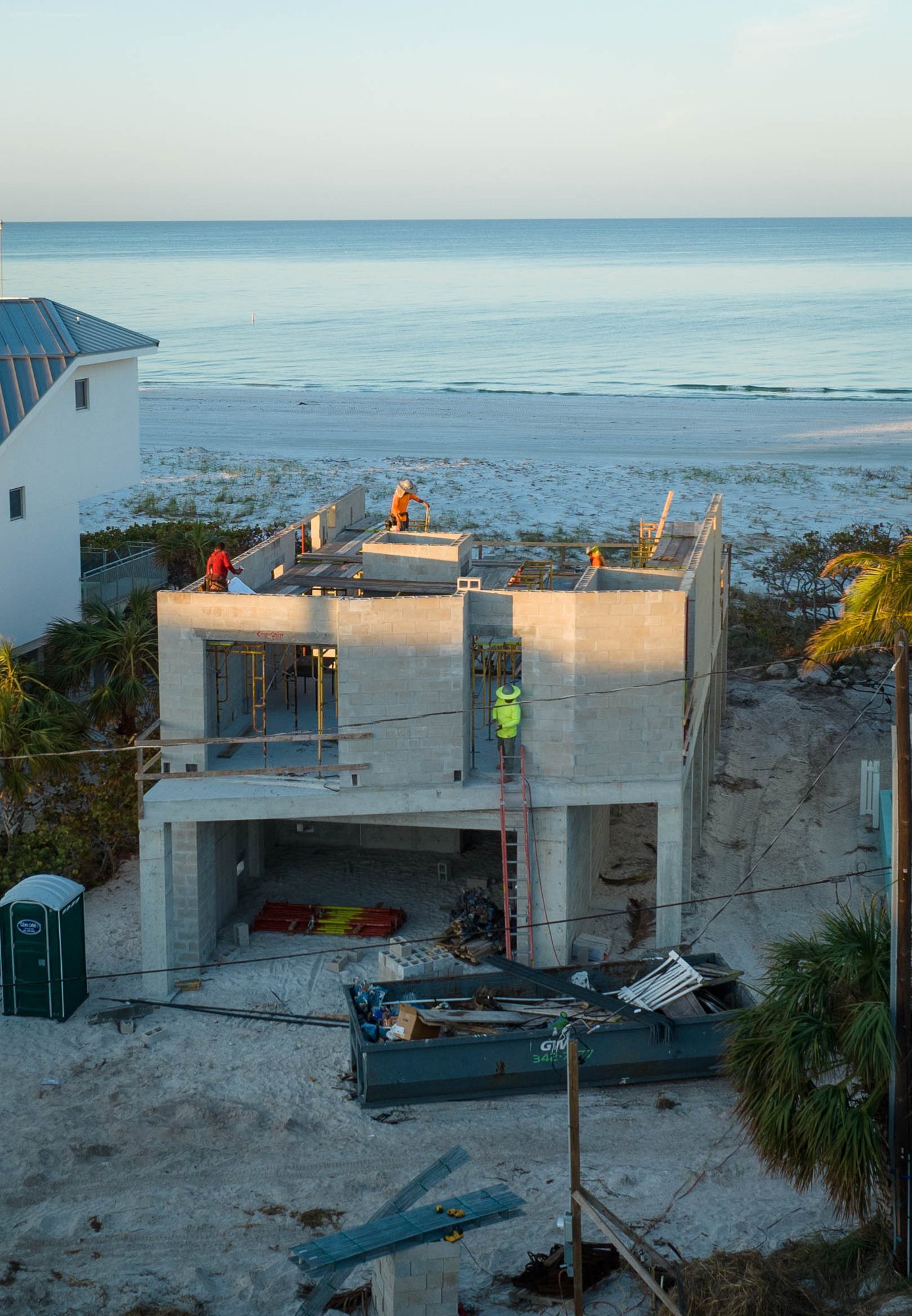View from the street of the masonry walls going up, with the Gulf beyond